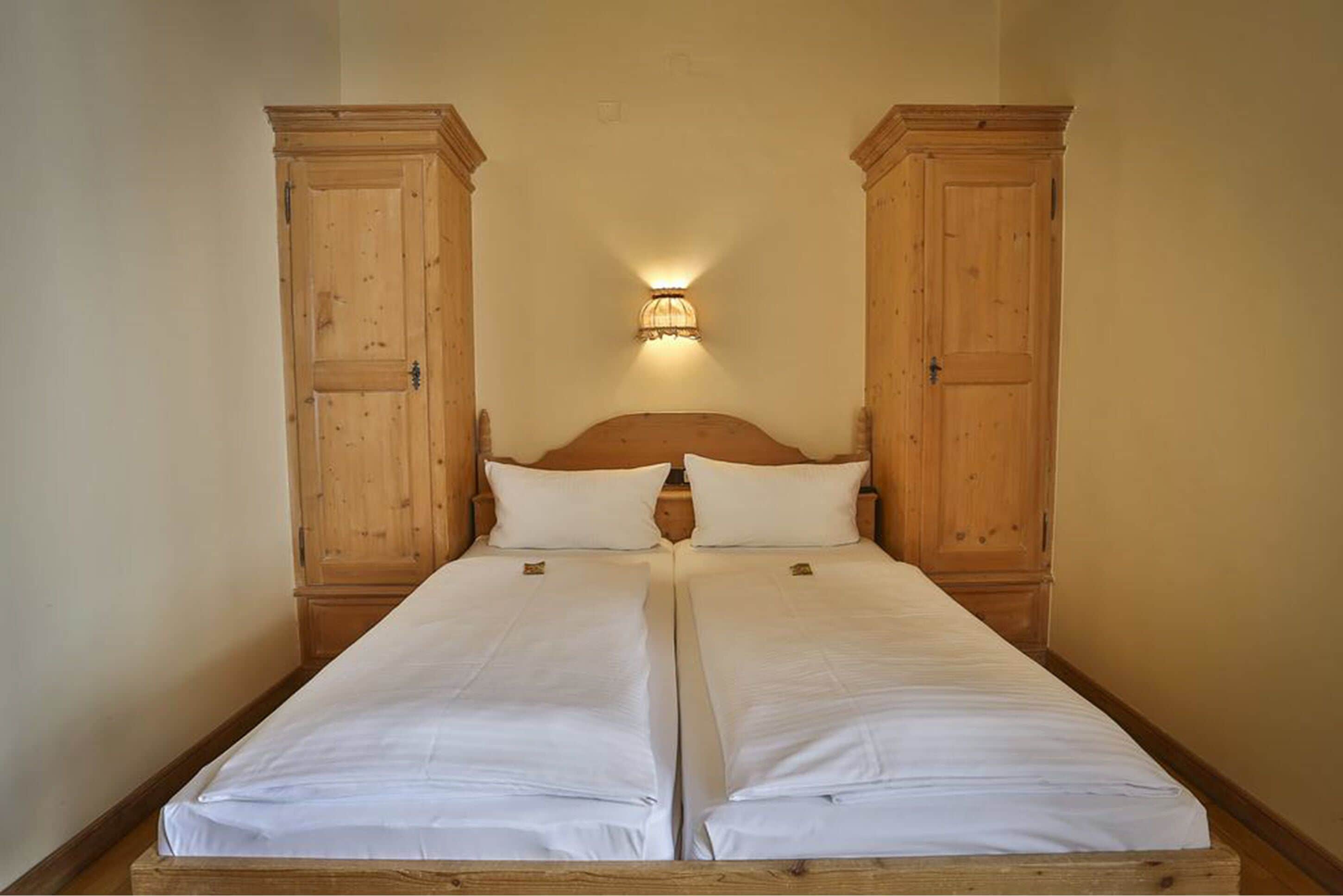 A double bed with a wooden headboard and two wooden cabinets on either side.
