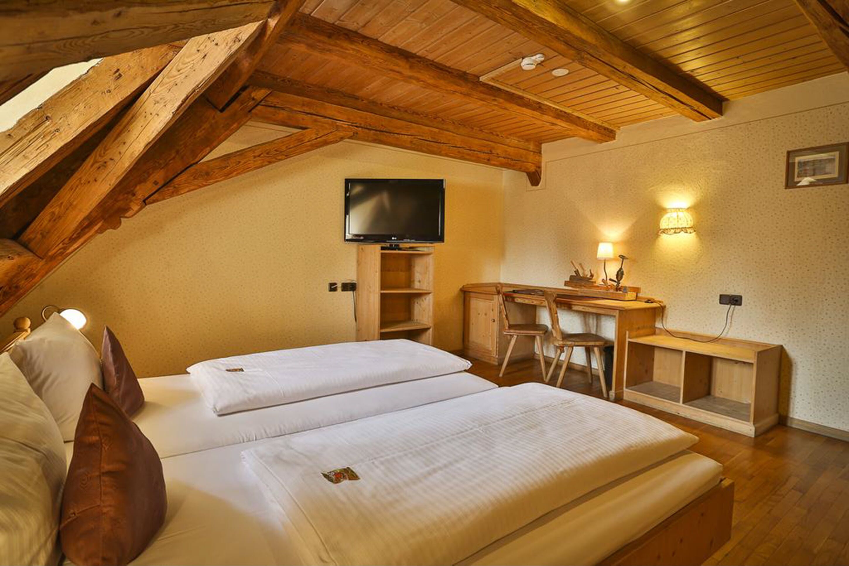 A cozy room with two beds, a desk, and a TV.