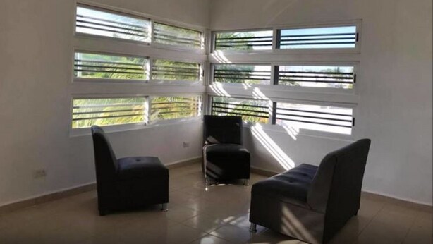 A spacious room with large windows, a ceiling fan, and two black chairs. - 330 Hotel Altabrisa (Mérida)