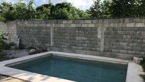 A rectangular swimming pool with a concrete edge, surrounded by a concrete wall and a gravel area. - 330 Hotel Altabrisa (Mérida)
