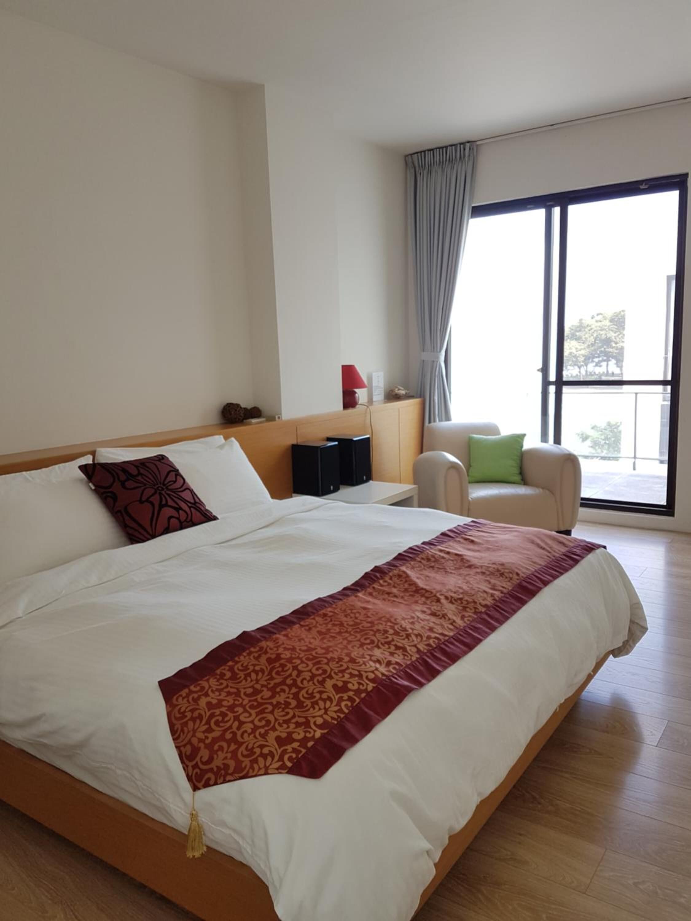 Ett hotellrum med en stor säng, ett skrivbord, en stol och en balkong med utsikt.