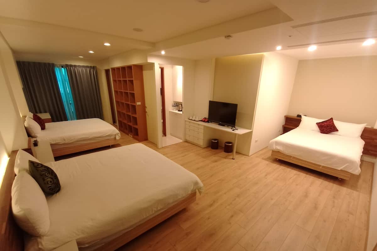Una camera d'albergo con due letti singoli, una TV, una scrivania e un armadio.