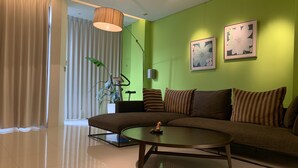 Una sala de estar moderna con una pared de acento verde, un sofá grande, una mesa de centro y una planta en maceta.