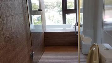 A modern bathroom with a wooden floor, a toilet, a bidet, and a glass shower enclosure.
