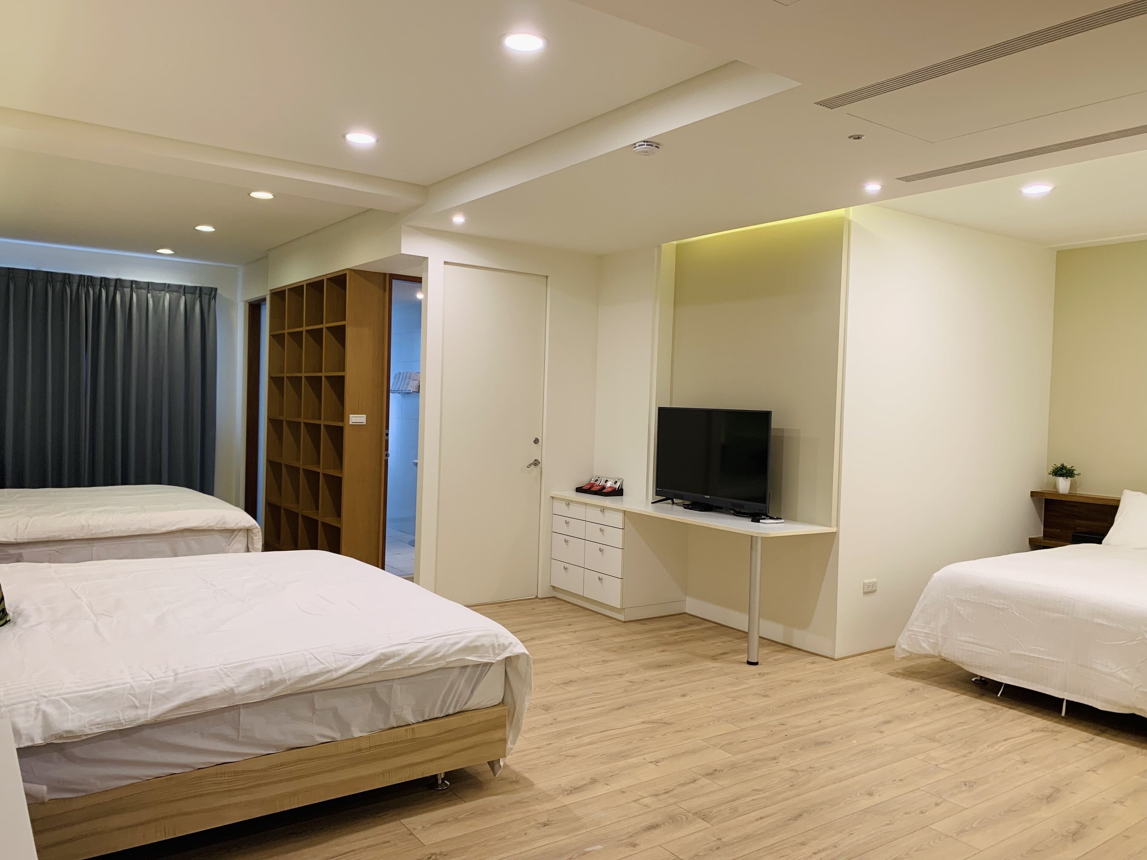 Une chambre avec deux lits, un téléviseur posé sur un meuble, une armoire et un petit bureau.