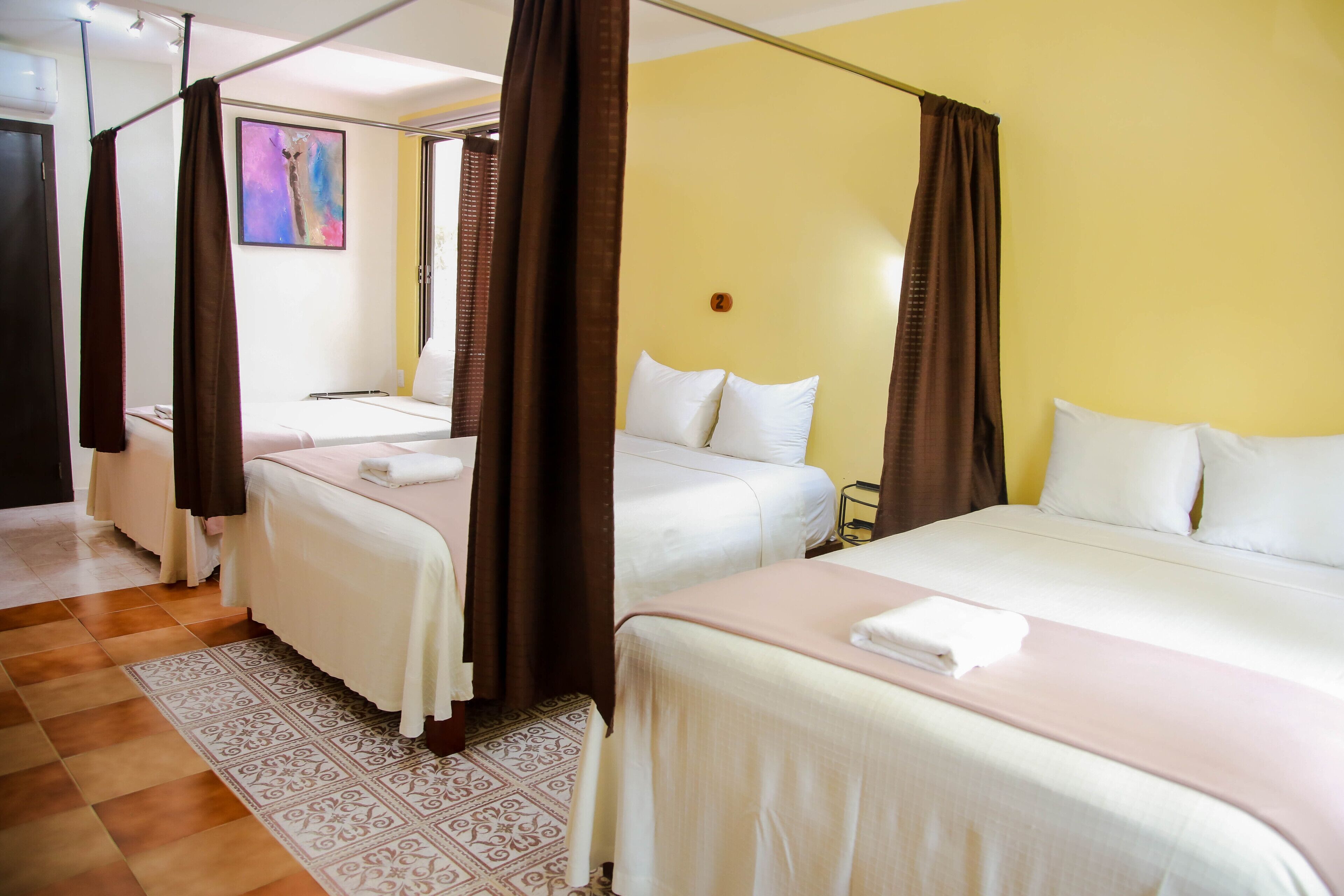 Une chambre d’hôtel avec deux lits, un tapis à motifs et un tableau accroché au mur.