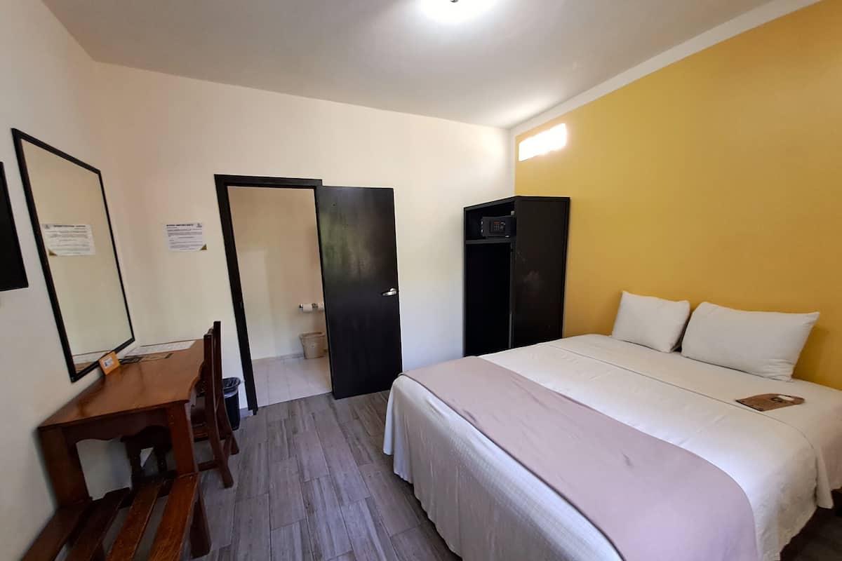 A hotel room with a bed, a desk, a chair, and a wardrobe.
