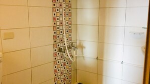 A bathroom with a black and white checkered floor, a toilet, and a shower with a patterned tile wall. - Hone Lane Business Hotel (Kaohsiung)