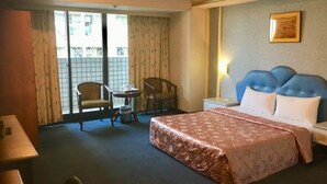 A hotel room with a bed, two chairs, a small table, a nightstand, and a window with curtains. - Hone Lane Business Hotel (Kaohsiung)