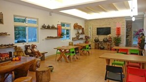Una habitación acogedora con una mesa y sillas de madera, un televisor y estantes con adornos.