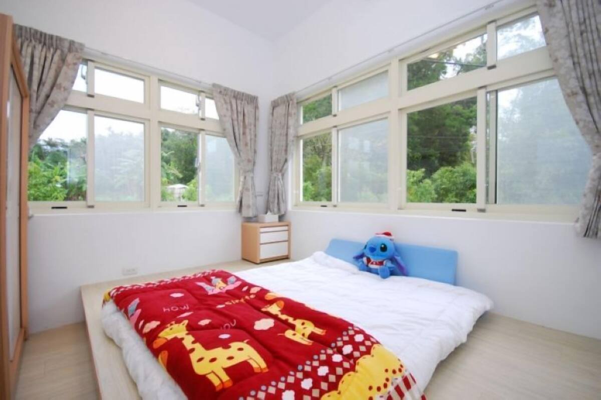 A bedroom with a bed, a nightstand, and a window with curtains.