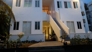 A modern two-story building with a central staircase, large windows, and a well-lit entrance. - Hotel Lady Nina (Baler)