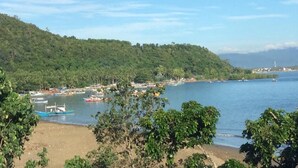 A coastal area with boats docked near the shore, surrounded by lush green hills. - Hotel Lady Nina (Baler)