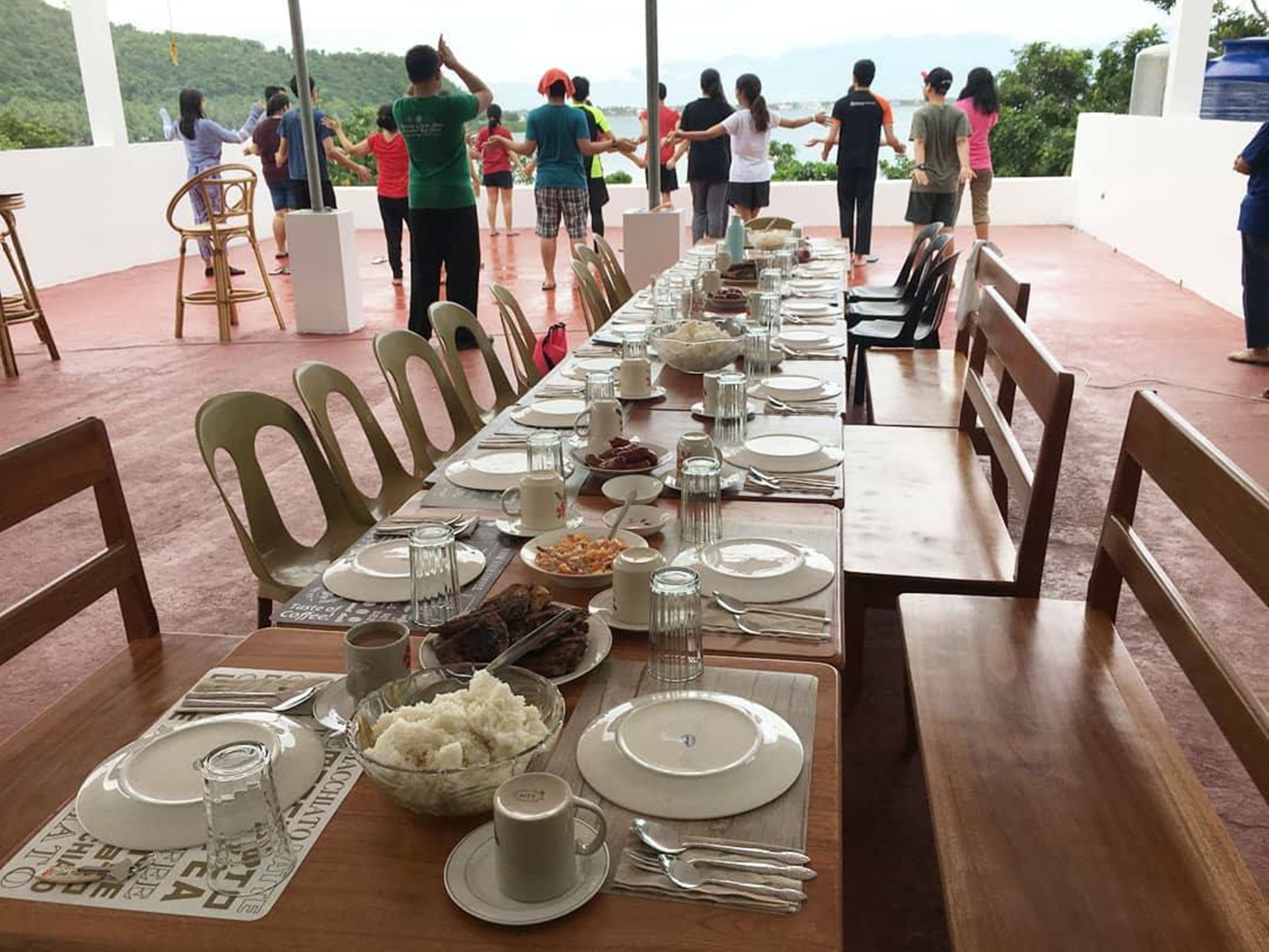 Una larga mesa de comedor preparada para una comida, con sillas a ambos lados, con vistas a un paisaje pintoresco.