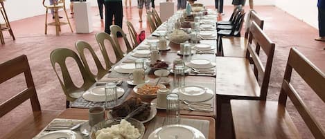 Una larga mesa de comedor preparada para una comida, con sillas a ambos lados, con vistas a un paisaje pintoresco.