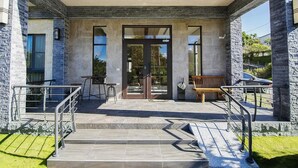 A modern building entrance with a stone facade, a glass door, and outdoor seating. - Hu An-The Lakeside House (Yuchi)