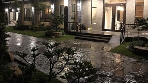 A two-story building with a stone facade, a well-lit entrance, and a paved pathway leading to the door. - Hu An-The Lakeside House (Yuchi)