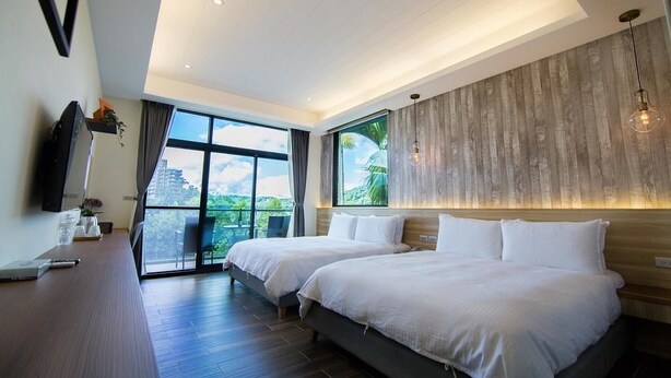 A modern hotel room with two beds, a large window offering a view of greenery, and a wooden accent wall. - Hu An-The Lakeside House (Yuchi)