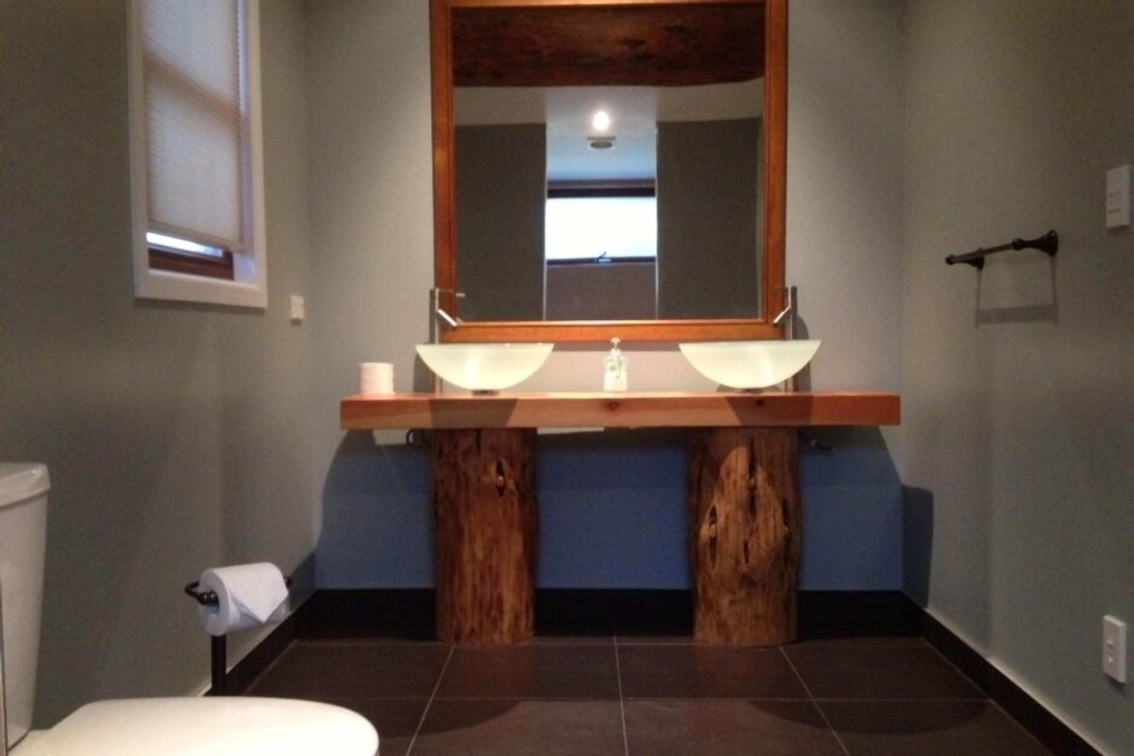 A bathroom with a wooden vanity, two sinks, and a mirror above.