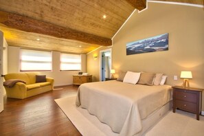 Relax in this serene bedroom with a large bed, bedside tables, and a beautiful mountain landscape painting above.