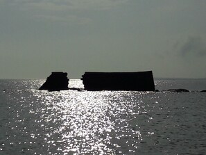 Un bateau sur une mer calme, la lumière du soleil se reflétant sur l’eau.