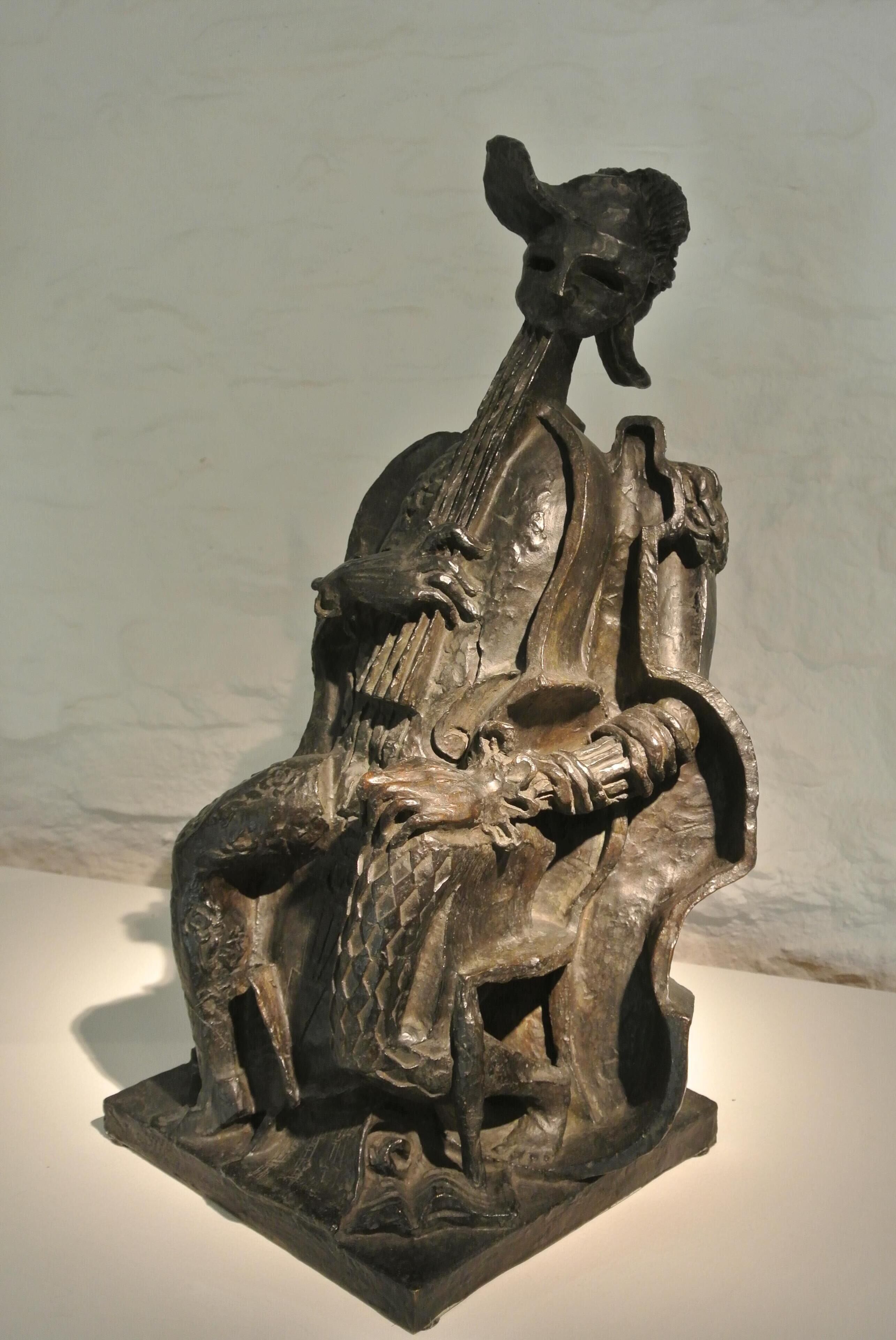 A sculpture of a seated figure with a long beard, possibly a historical or religious figure, on a pedestal.