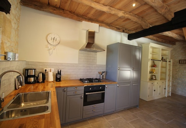 A kitchen with a wooden ceiling, stainless steel sink, and grey cabinets.