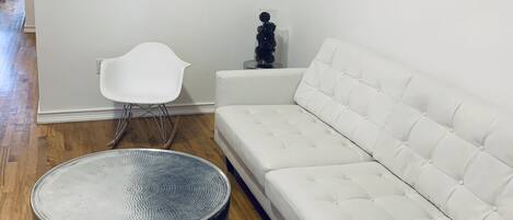 A modern living room with a white sofa, a round coffee table, and a poster of The Beatles on the wall.