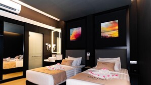 A hotel room with two beds, a large mirror, artwork on the walls, and a modern design.