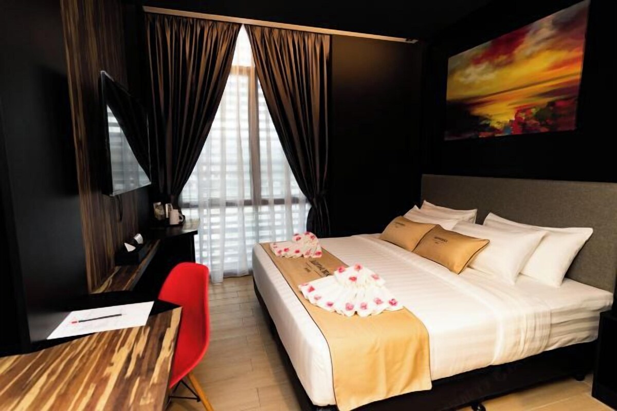 A hotel room with a bed, a desk, a chair, and a large window with curtains.