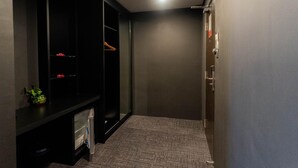 A hallway with a dark-colored wardrobe, a small plant, and a carpeted floor.