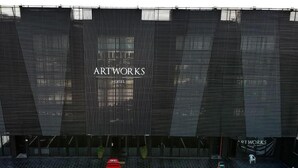 A modern building with a large digital display advertising 'ARTWORKS HOTEL'.