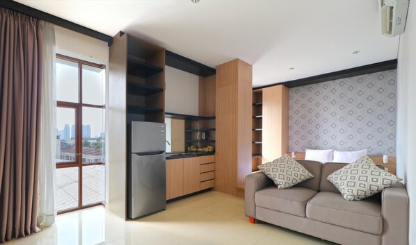 Eine moderne Wohnung mit Küche, einem Sofa mit gemusterten Kissen und Blick auf die Stadt durch ein großes Fenster.