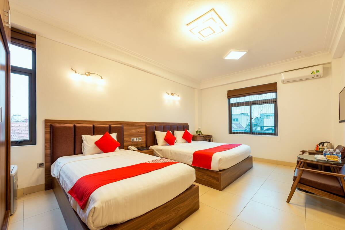 Une chambre d’hôtel avec deux lits, un bureau et une chaise.