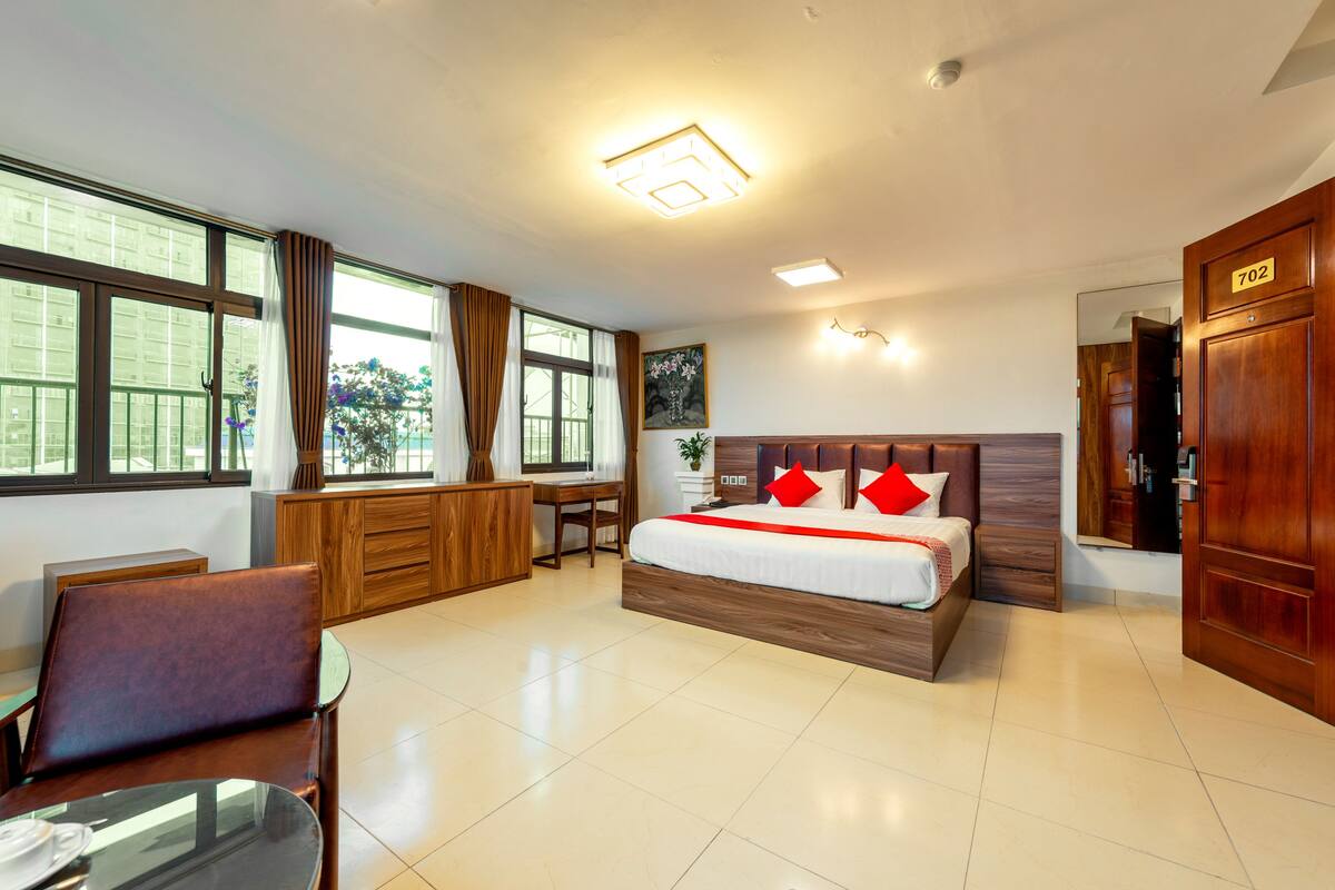 Une chambre d’hôtel avec un grand lit, un bureau, une chaise et une vue sur l’extérieur.