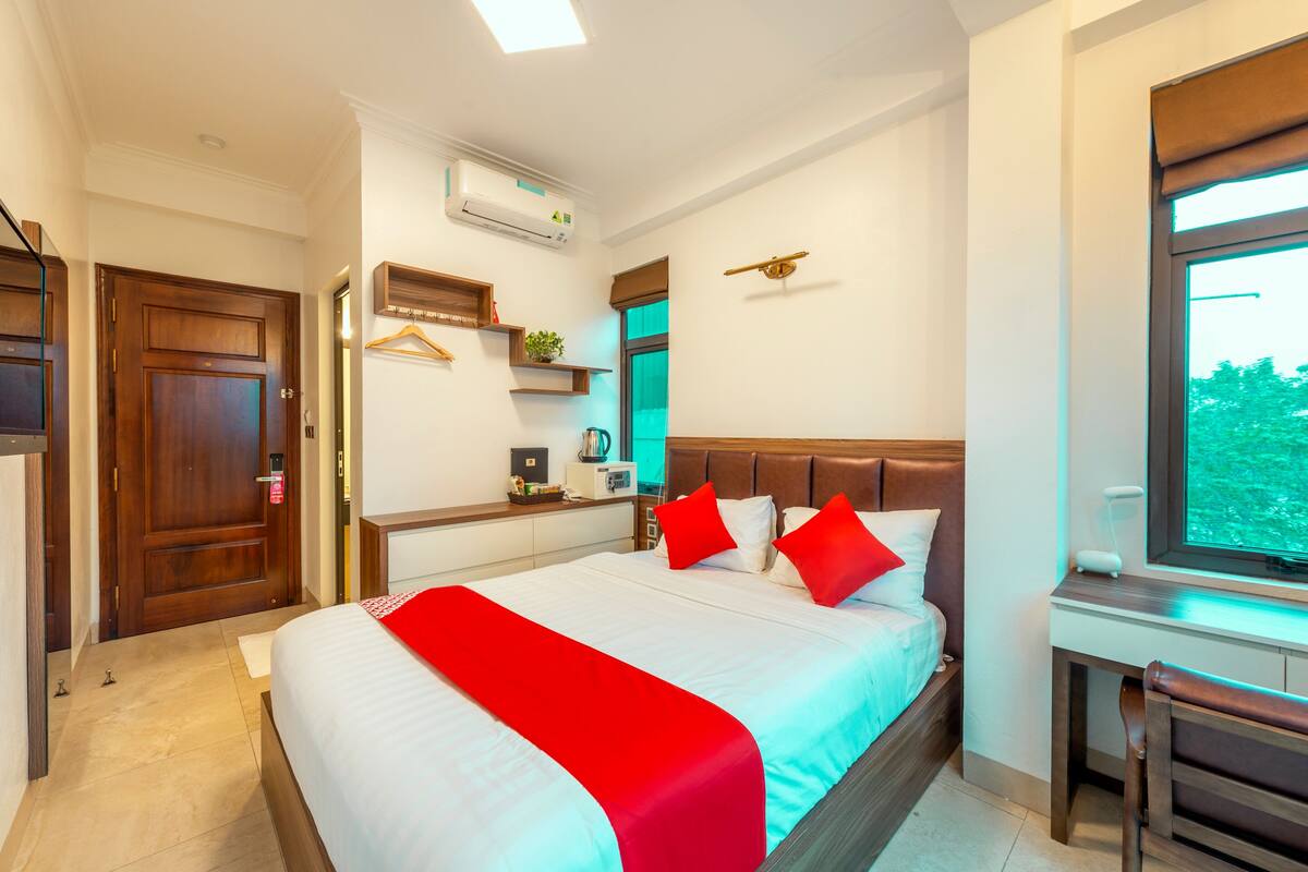 Une chambre d’hôtel avec un grand lit, un bureau, une chaise, une fenêtre et une porte.