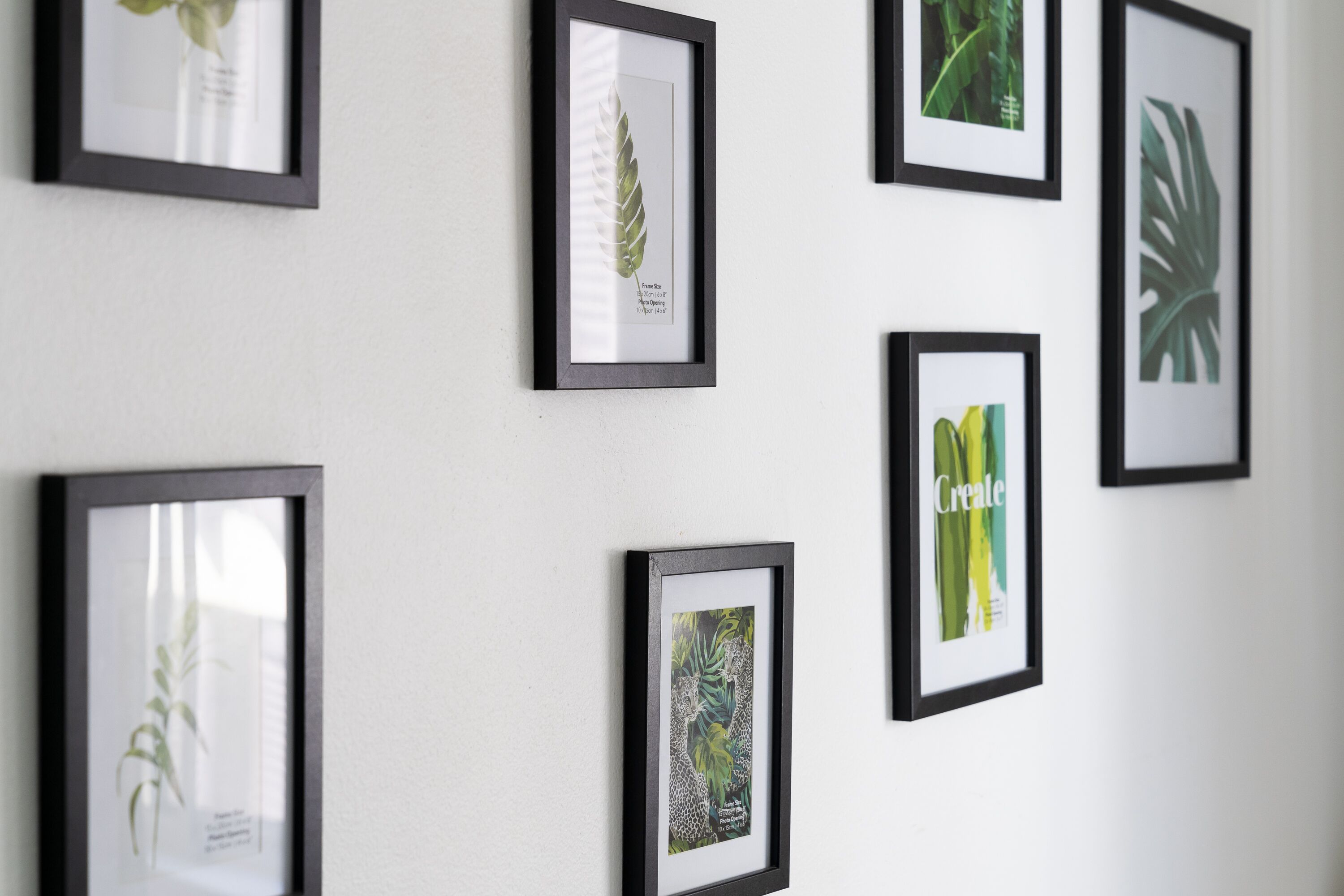 Una pared decorada con varios cuadros de motivos botánicos.