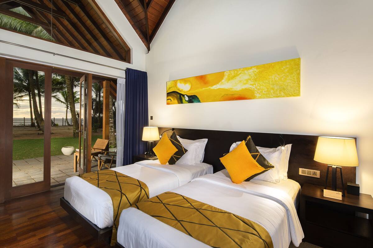 A hotel room with two beds, a large window, and a painting on the wall.