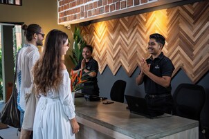 Un mostrador de recepción con pared de diseño en zigzag, una computadora portátil y un teléfono inteligente encima.