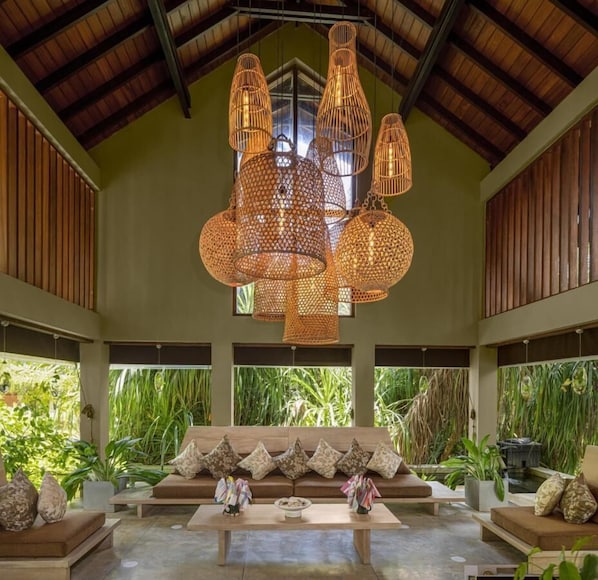 A spacious indoor area with a high ceiling, a large sofa with patterned cushions, and multiple hanging wicker lamps. - Ayana Sea (Wadduwa)