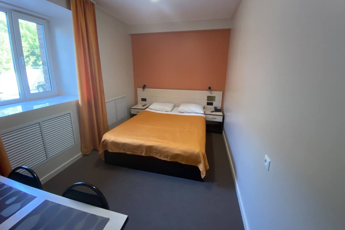 Une chambre d’hôtel avec un lit, un bureau et une fenêtre avec des rideaux.