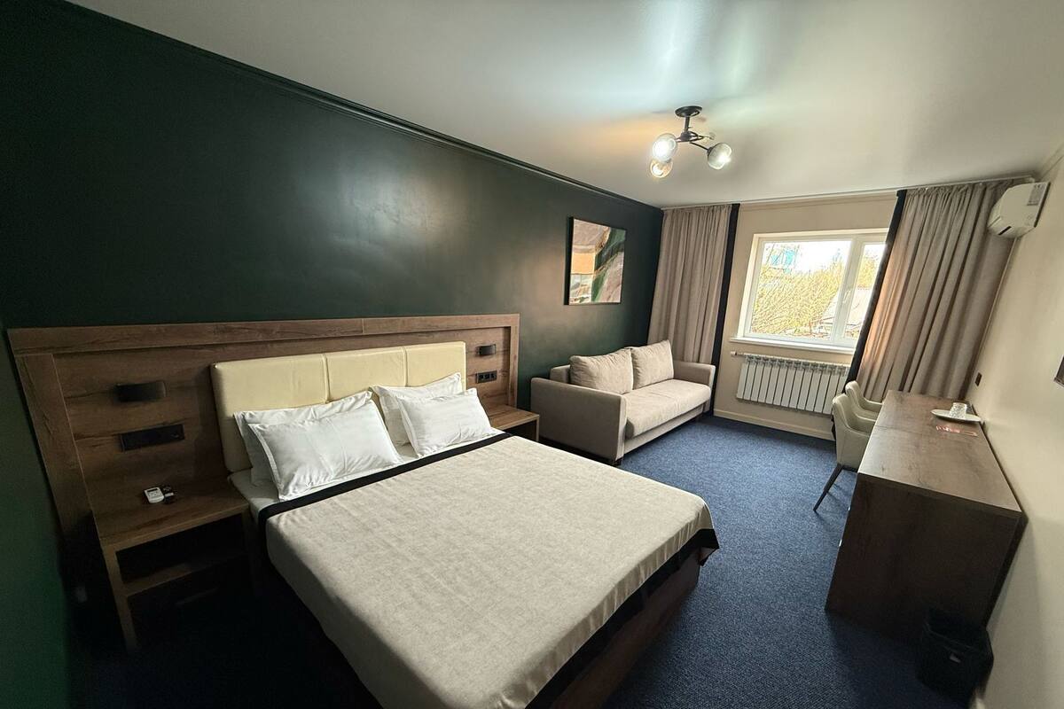 Une chambre d’hôtel avec un grand lit, un bureau, une chaise et un canapé.
