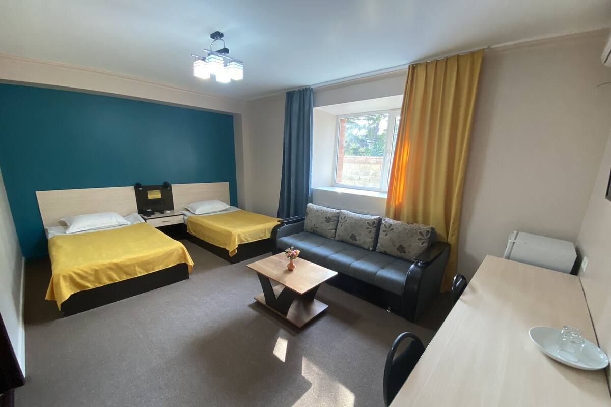 Une chambre d’hôtel avec deux lits simples, un canapé, un bureau et une petite table.
