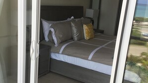 Ein Schlafzimmer mit Bett, Nachttischen, einer Lampe und Blick ins Freie.