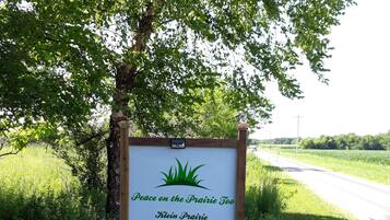 A sign with text "Peace on the Prairie Too" and "Klein Prairie" under a tree.