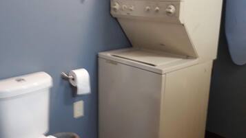 A compact laundry room with a washing machine and dryer, a toilet, and a wall-mounted laundry sign.