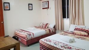 Ein Hotelzimmer mit zwei Betten, einem Holztisch, einem Fenster mit Vorhängen und einer Klimaanlage.