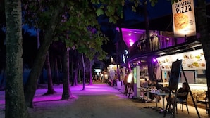 Nachts belebte Straße mit einem Restaurant für Fladenpizza.