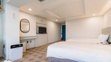 A hotel room with a bed, a small kitchenette, a mirror, and a fire extinguisher.