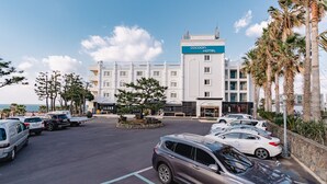 Um hotel com design moderno, estacionamento e palmeiras.